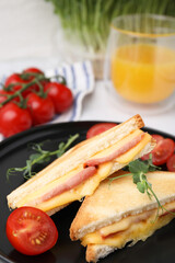 Pieces of toasted bread with melted cheese, ham and tomatoes on table