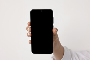 Woman holding smartphone with blank screen on white background, closeup