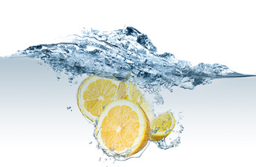 Fresh lemons falling into water on white background