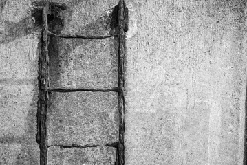 An iron staircase rusted by the sea air on a cement wall. Black and white. background.