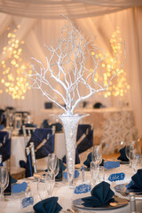 Beautiful glass vase centerpiece filled with glass rocks atwedding reception table in warm...