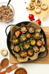 Stuffed mushrooms in frying pan and ingredients on white background, top view