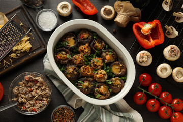 Stuffed mushrooms, towel and ingredients on wooden background, top view