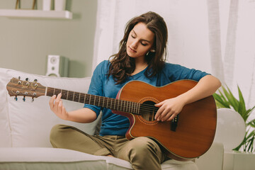 Concentrating woman, playing guitar, sitting serenely
