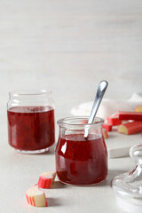 Rhubarb jelly in a jar with fresh rhubarb stems