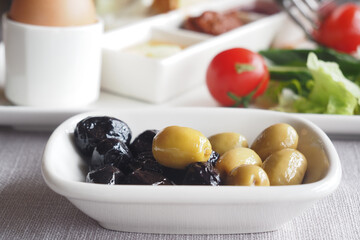 Collection of black and green olives with leaves.