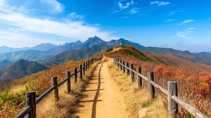 Fototapeta premium A scenic mountain trail leads through vibrant autumn foliage under a clear blue sky, inviting adventure and exploration.