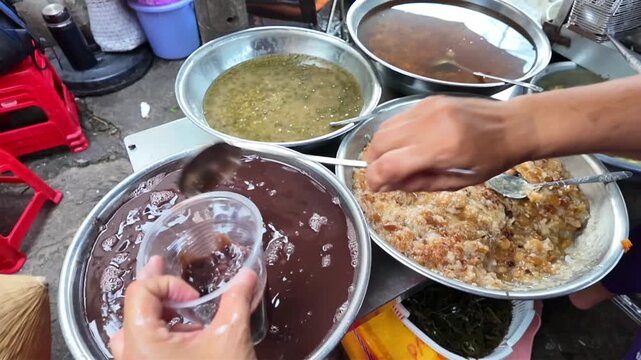 Vietnamese street food, sweet soup is tradition desserts, woman hand scooping che, sugared dishes from deverse bean, banana and coconut milk at outdoor stalls