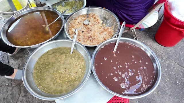 Vietnamese street food, sweet soup is tradition desserts, woman hand scooping che, sugared dishes from deverse bean, banana and coconut milk at outdoor stalls