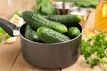 Saucepan with fresh cucumbers for preservation on wooden background