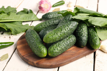 Board with fresh cucumbers for preservation on light wooden background