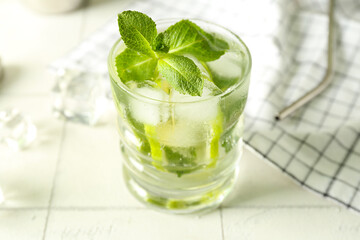 Glass of tasty mojito on light tile background