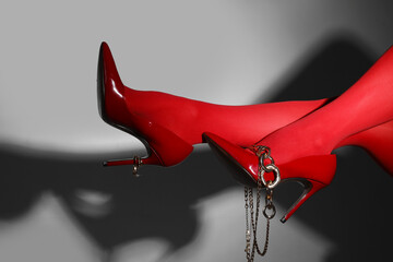 Female legs in red tights and high heels with accessories on grey background