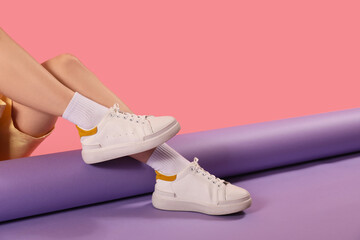 Female legs in stylish sneakers and socks on color background