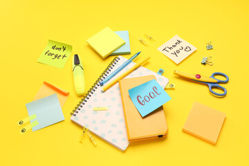 Sticky notes with notebooks and stationery on yellow background