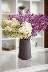 Vase with beautiful lilac flowers on coffee table in interior of living room
