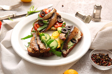 Plate of tasty sandwiches with canned smoked sprats on table