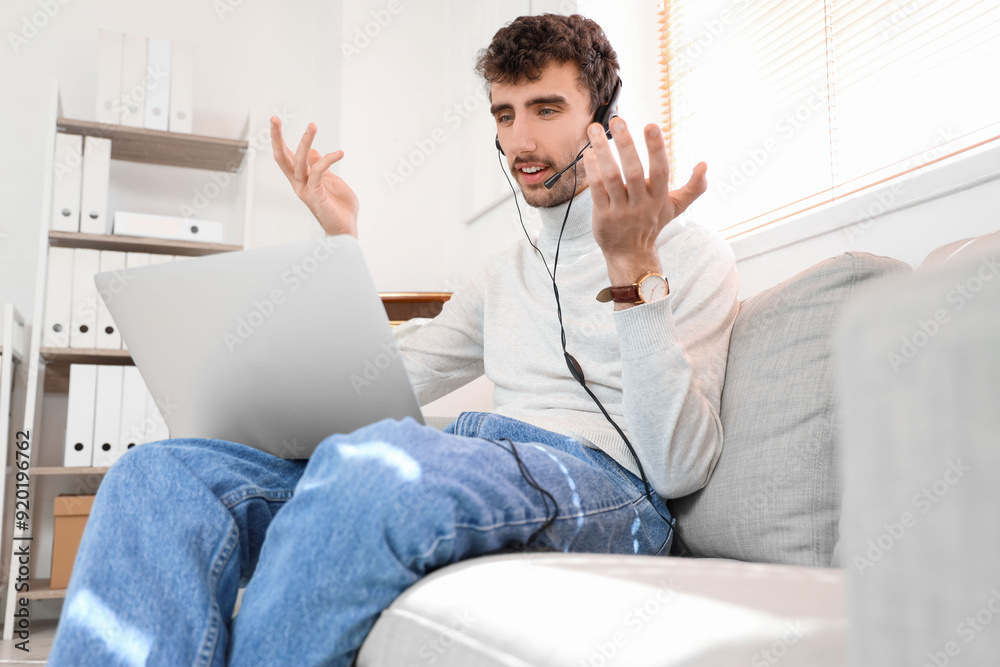 Poster male technical support agent with laptop sitting on sofa