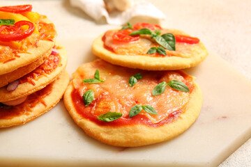 Board with different tasty mini pizzas on white background