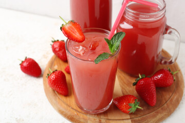Bottle with mason jar and glass of tasty strawberry juice on white table