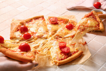 Women taking slices of tasty pizza margarita on beige tile table