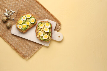 Tasty toasts with quail eggs, avocado and cucumber on beige background