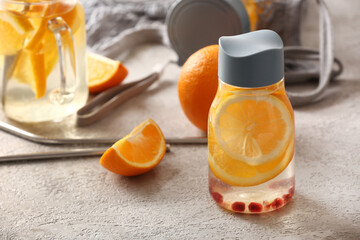 Sports bottle of infused water with orange slices on grey table