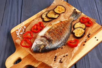 Board with tasty grilled dorado fish on blue wooden background
