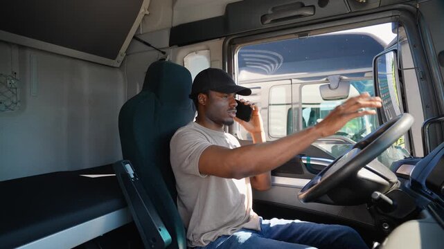 African American trucker talking on the phone with a customer while sitting in his truck