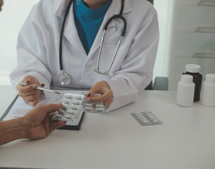 Doctor prescribing medicine giving pills to senior grandmother patient at hospital.