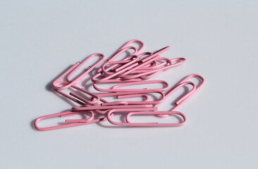 Group of pink paper clips scattered on a light-colored surface