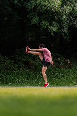 Young man lifting his legs to warm up before going for a run. Vertical