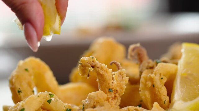 Squizing lemon juice on fried shrimps.