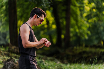 Athlete wearing sunglasses looking at his smart watch during a training session