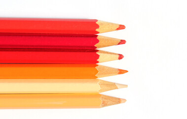 Row of red, orange and yellow pencils against a white background