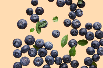 Flying sweet fresh blueberries and leaves on orange background