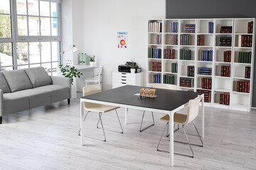 Interior of medical office with table, sofa and bookshelf