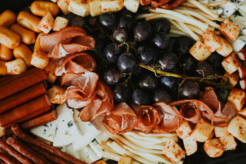 macro shooting of various snacks in the form of meats and cheeses with grape on a plate 