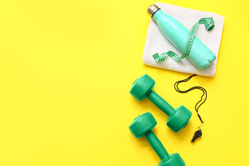 Measuring tape, towel and sports equipment on yellow background