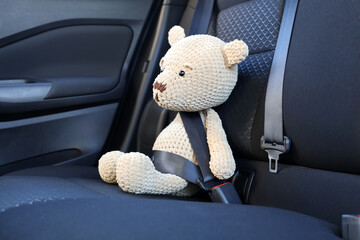 Fastened toy bear on seat in car