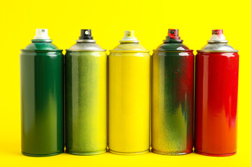 Many spray paint cans on yellow background