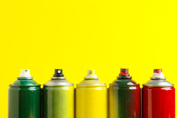 Many spray paint cans on yellow background