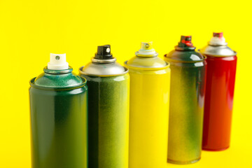 Many spray paint cans on yellow background