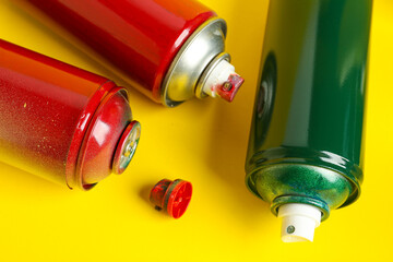 Spray paint cans on yellow background