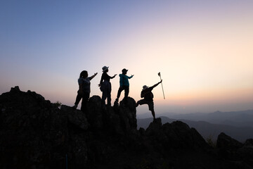 Silhouette of a group of climbers on a mountaintop. Success, teamwork and unity.