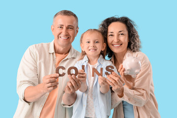 Fototapeta premium Happy family with piggy bank and word COINS on blue background