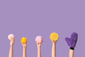 Female hands with massage glove and bath sponges on purple background