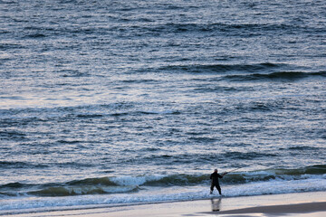 Silhouette of a fisherman standing on the beach in front of sea in dawn