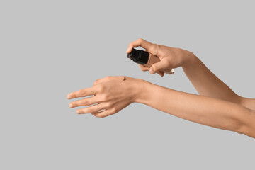Fototapeta premium Woman applying makeup foundation on grey background