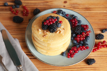 Plate of sweet pancakes with different fresh berries on wooden background